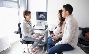 Pregnant couple talking with healthcare provider with sonogram on the screen